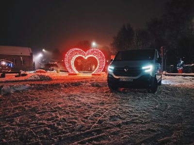 Oświetlone serce i zaparkowany van na zaśnieżonym placu nocą przy kościele