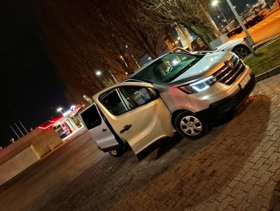 Biały van Renault zaparkowany nocą przy oświetlonej ulicy z otwartymi drzwiami bocznymi